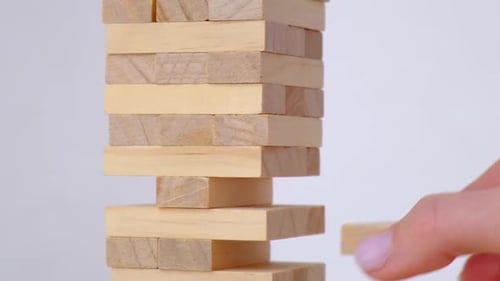 Female Hand Playing Wooden Block Removal Tower Game at Home