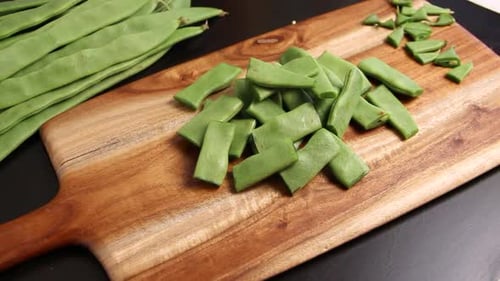 Woman's hands cutting piattoni green beans close up