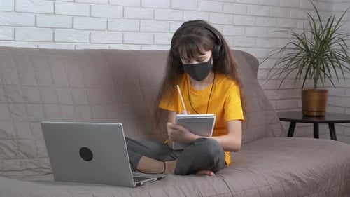 Girl Learning Online Wearing Mask and Headphones