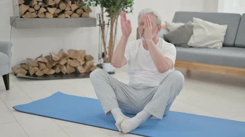 Senior Man Meditating at Home on Yoga Mat