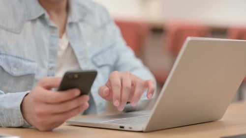 Männliche Hände benutzen Smartphone beim Tippen auf Laptop Nahaufnahme