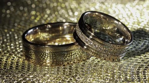 Wedding Gold Rings Lying on Shiny Glossy Surface, Shining with Light, Close-up