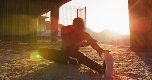 Man Stretches Leg Outdoors at Sunset