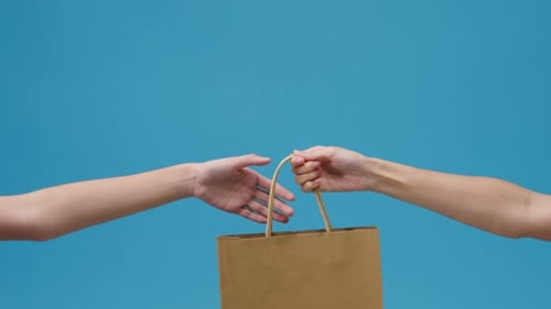 Hands Giving and Receiving a Brown Paper Bag