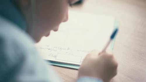 CU Boy Sit in Headphones and Do School Homework Writes a Ballpoint Pen in a Notebook