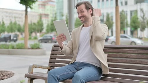Man Using Tablet and Celebrating Success Outdoors