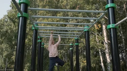 Little Girl Training on a Chinup Bar Outdoors