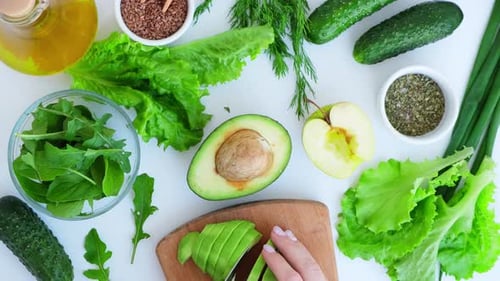 Woman Cooking Salad of Fresh Green Vegetables and Herbs
