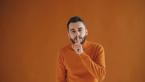 Retrato de joven guapo haciendo gesto de silencio tocando la boca con el dedo