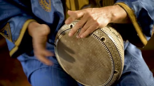Enge Aufnahme eines Mannes in marokkanischer Kleidung, der arabisches Doumbek, Darbuka oder Derbeki spielt