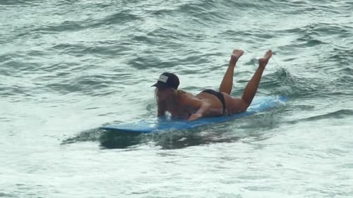 A young woman surfing in a bikini on a longboard surfboard.