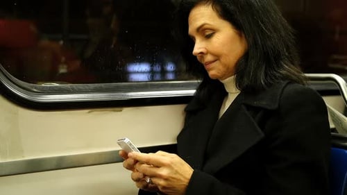 Woman Using Cellphone on a Subway Train