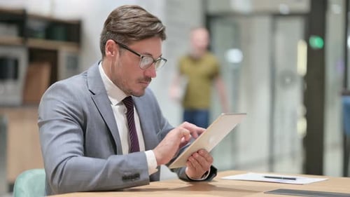 Serious Businessman Using Tablet in Office