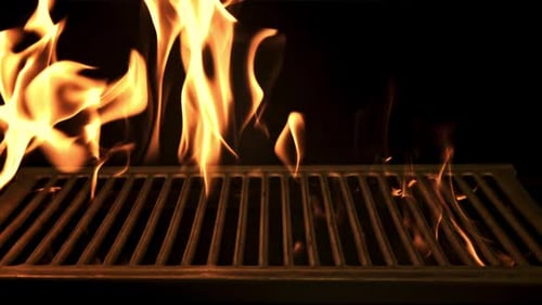 Eine helle Feuerflamme brennt durch den Grill