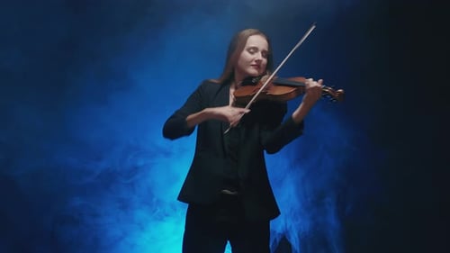 Young Beautiful Woman Playing a Melody on Violin. Smoky Dark Studio