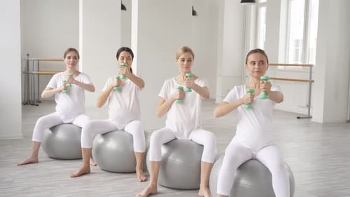 Pregnant Women Exercising Together in Bright Studio