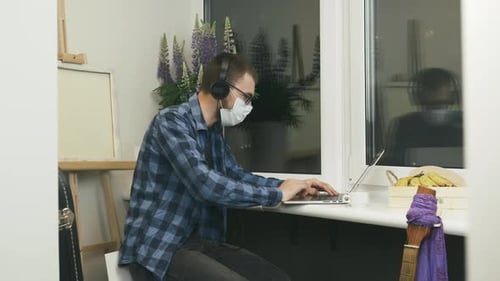 Man in protective mask making online video call by webcam and talking with friends & family at home