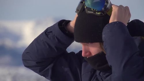 Portrait of a young man snowboarder on a scenic snow covered mountain top