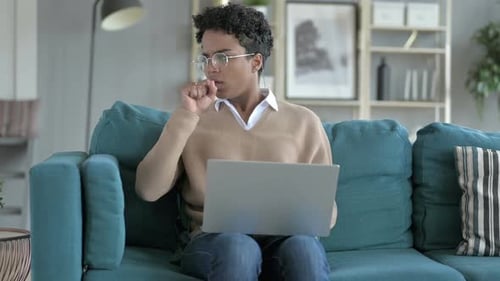 Young Adult Coughing While Sitting on Couch