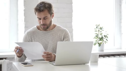 Man reviewing paperwork while working at desk