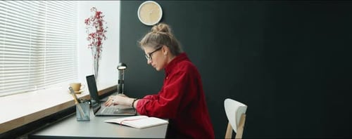 Businesswoman Using Laptop and Taking Notes in Office