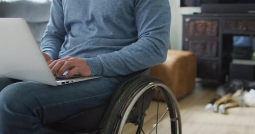 Man in Wheelchair Using Laptop Indoors