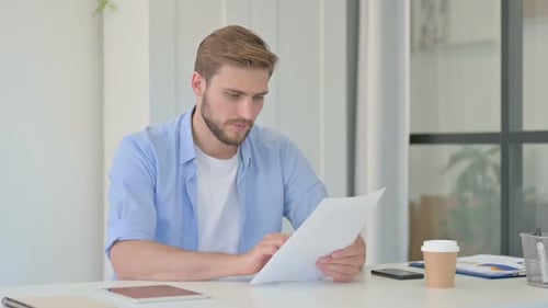 Man Reviewing Documents at Desk in Office