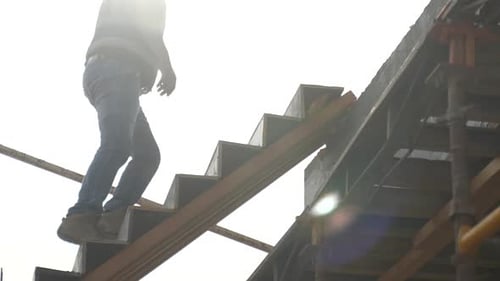 Construction Worker Ascending Wooden Steps in Bright Sunlight