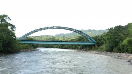 Luftaufnahme über einen breiten Fluss mit einer Metallfachwerkbrücke, der die Brücke überquert