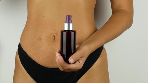 Beautiful lady smears her belly with cream. Sensitive hand massage. A woman after childbirth