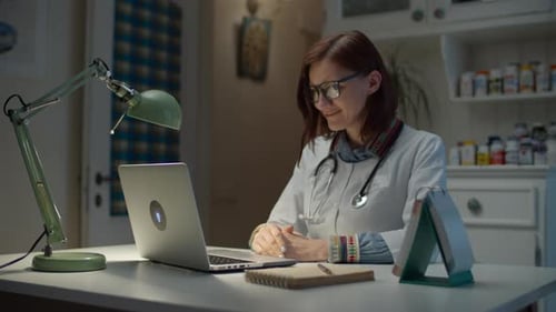 Young 30s female doctor talking online with sick patient and making notes