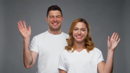 Pareja con camisetas blancas agitando la mano