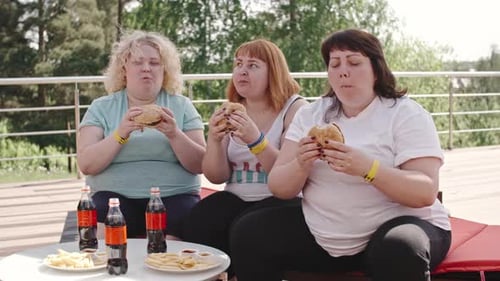 Women Enjoy Burgers, Fries, and Drinks Outside