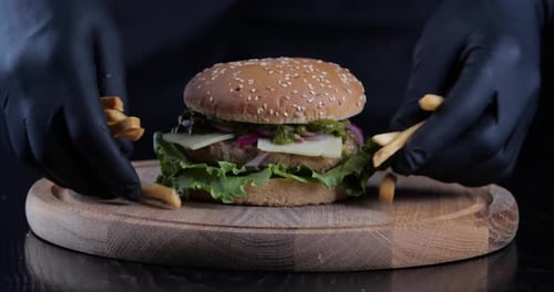 Foto recortada de manos masculinas con guantes negros sosteniendo deliciosas patatas fritas amarillas y poco saludables pone patatas