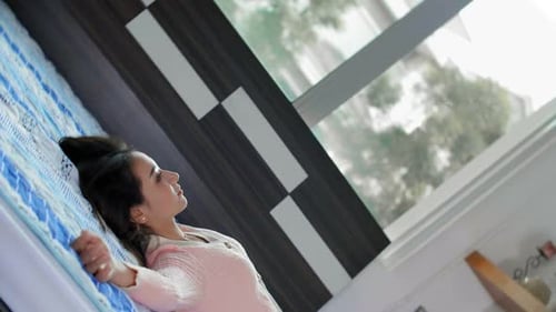 Young Woman Lying on Bed Relaxing in Bedroom