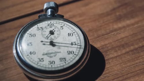 An Antique Stopwatch Lies on Wooden Table and Counts the Seconds Timelapse