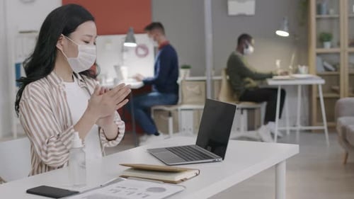Asian Woman Spraying Sanitizer in Office