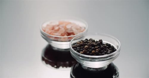 Pink Salt and Black Peppercorns in Glass Bowls