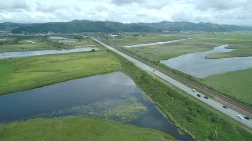 Aerial Drone View of Beautiful Natural Scenery of Road in Green Meadow with River Mountains in