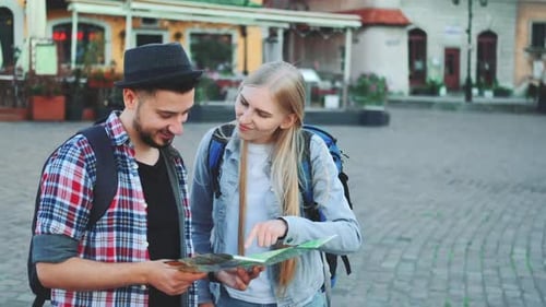 Trendiges Touristenpaar, das auf der Karte das notwendige Ziel findet und die Umgebung bewundert
