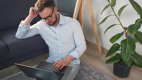 Man Sitting on Floor Working on Laptop