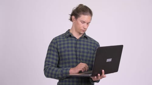 Man Using Laptop Indoors on Plain Background
