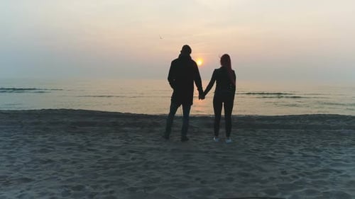 Couple Holding Hands on Beach at Sunrise