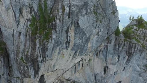 Aerial drone view of a man rock climbing up a mountain.