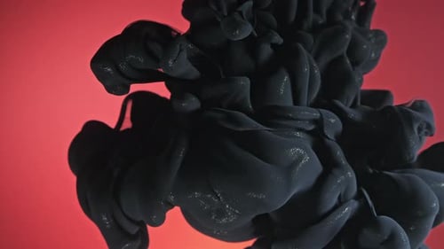 Black Ink Swirling in Water Against Red Background