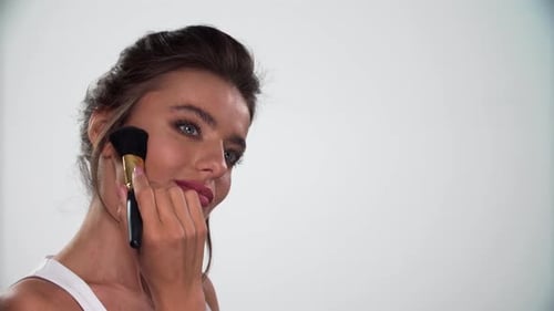 Woman Applies Makeup with a Brush in Studio