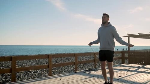 Man Exercising with Jump Rope on Beach Deck