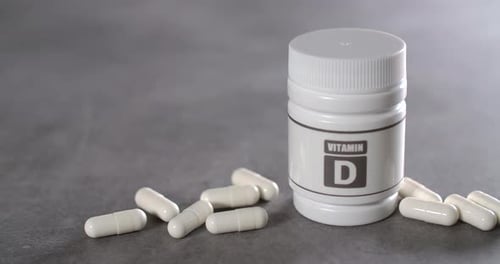Vitamin D Capsules Bottle and Pills on Table