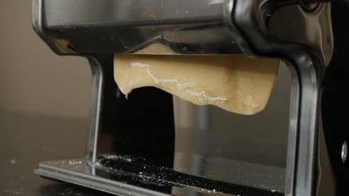 Dough Being Rolled Through Pasta Machine Close-Up
