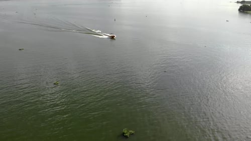 Luftaufnahme des Wakeboardens auf dem Fluss bei Sonnenuntergang. Freunde auf dem Boot haben Spaß, machen extreme Wassersportarten